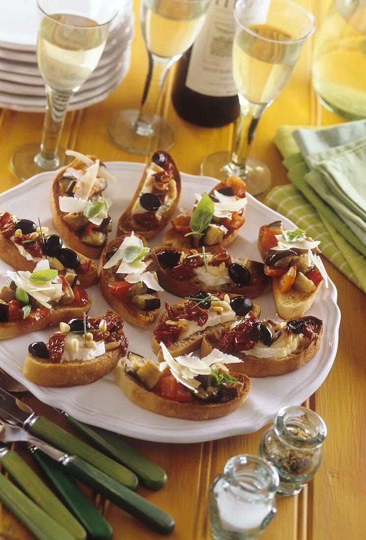Crostini mit Oliven und Parmesan auf Teller; Wein