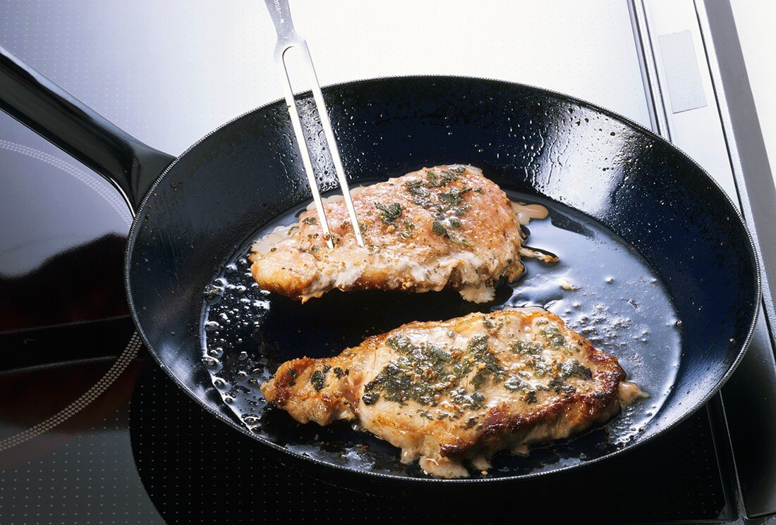 Frying pork chops with sage in cast-iron frying pan