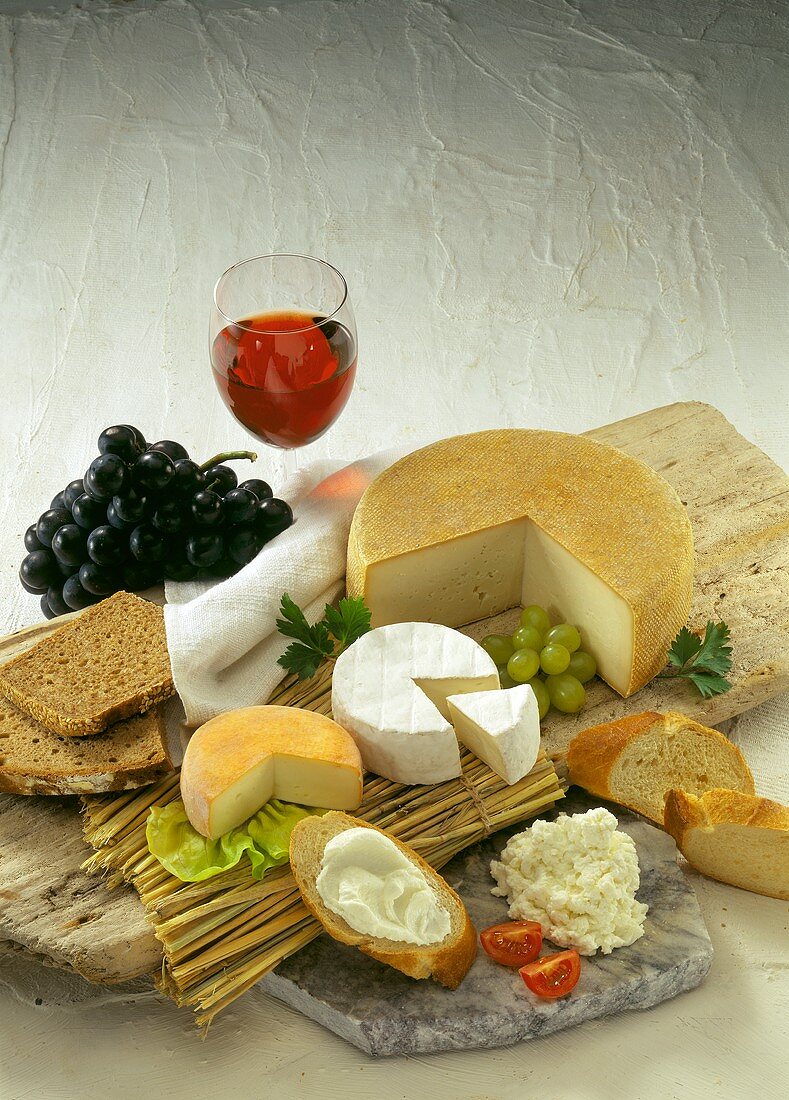 Various types of cheese with bread, grapes and red wine