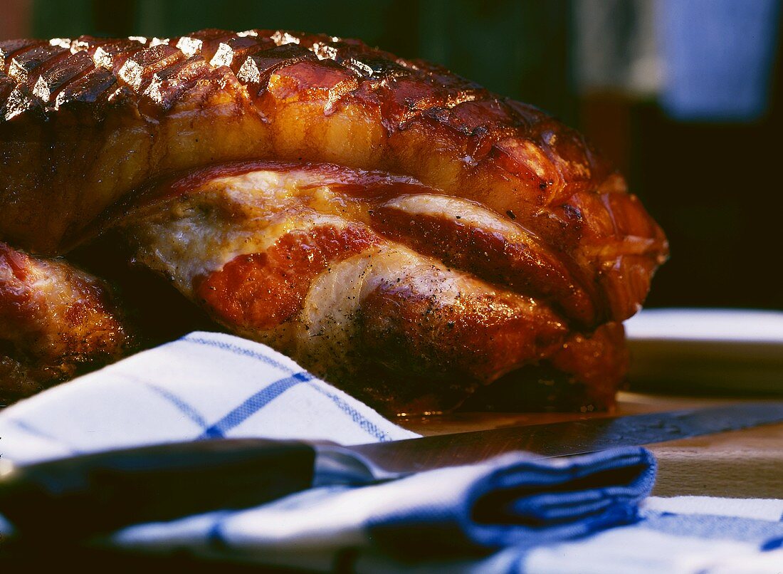 Roast pork with crackling behind tea towel and knife