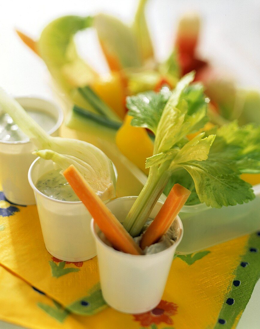 Vegetables snacks with dips in tubs on coloured napkins