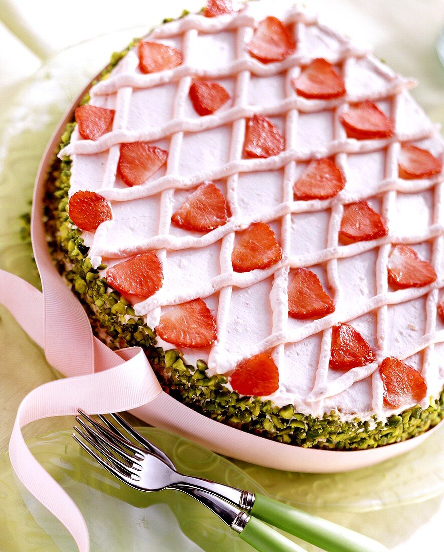 Erdbeer-Biskuit-Ei mit Pistazienrand und rosa Schleife