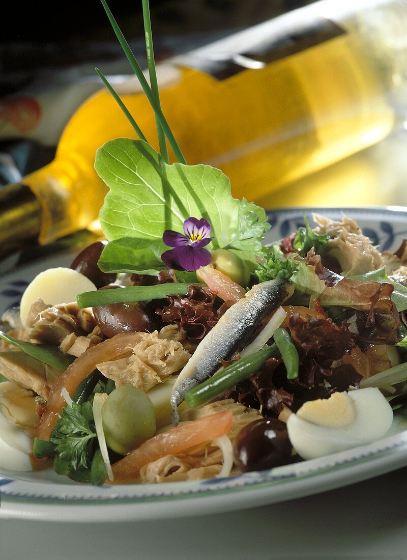 Salat mit Thunfisch, Sardinen und Gemüse; Weissweinflasche