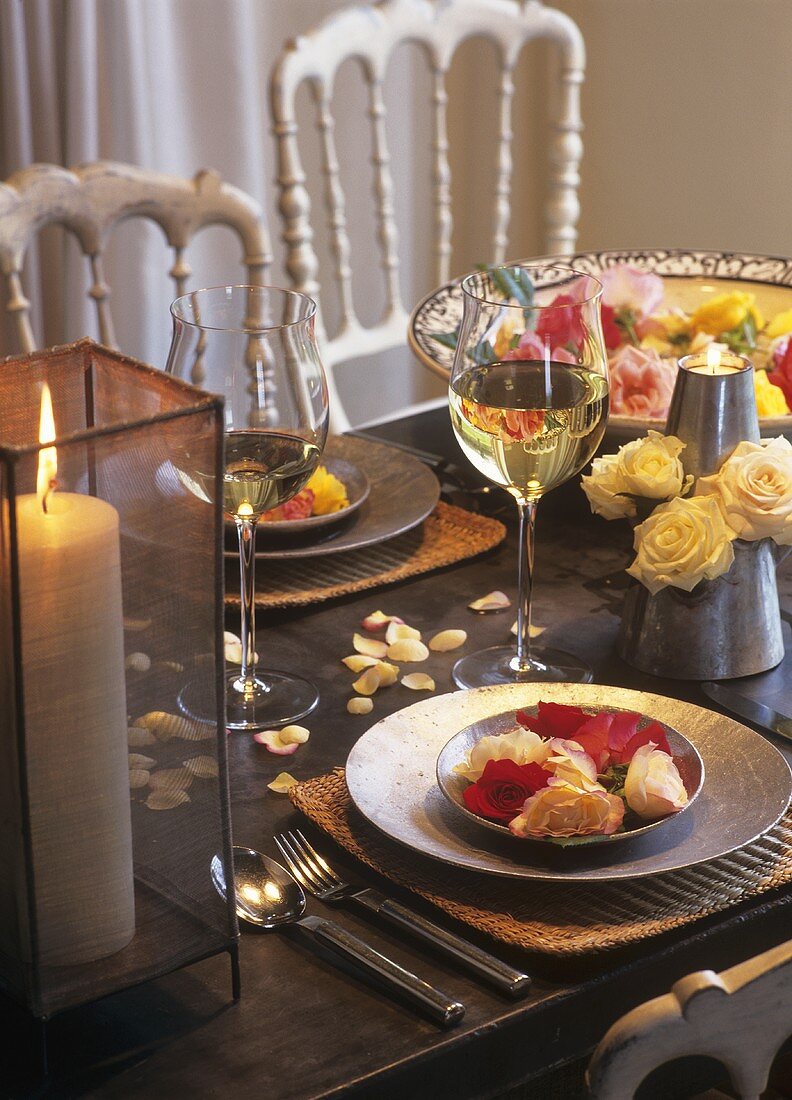 Roses as table decoration, candle and white wine glasses