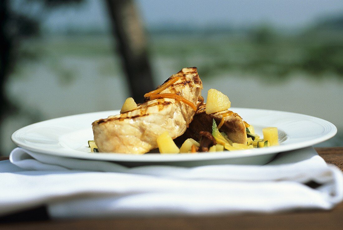 Grilled sturgeon with vegetables on plate in open air