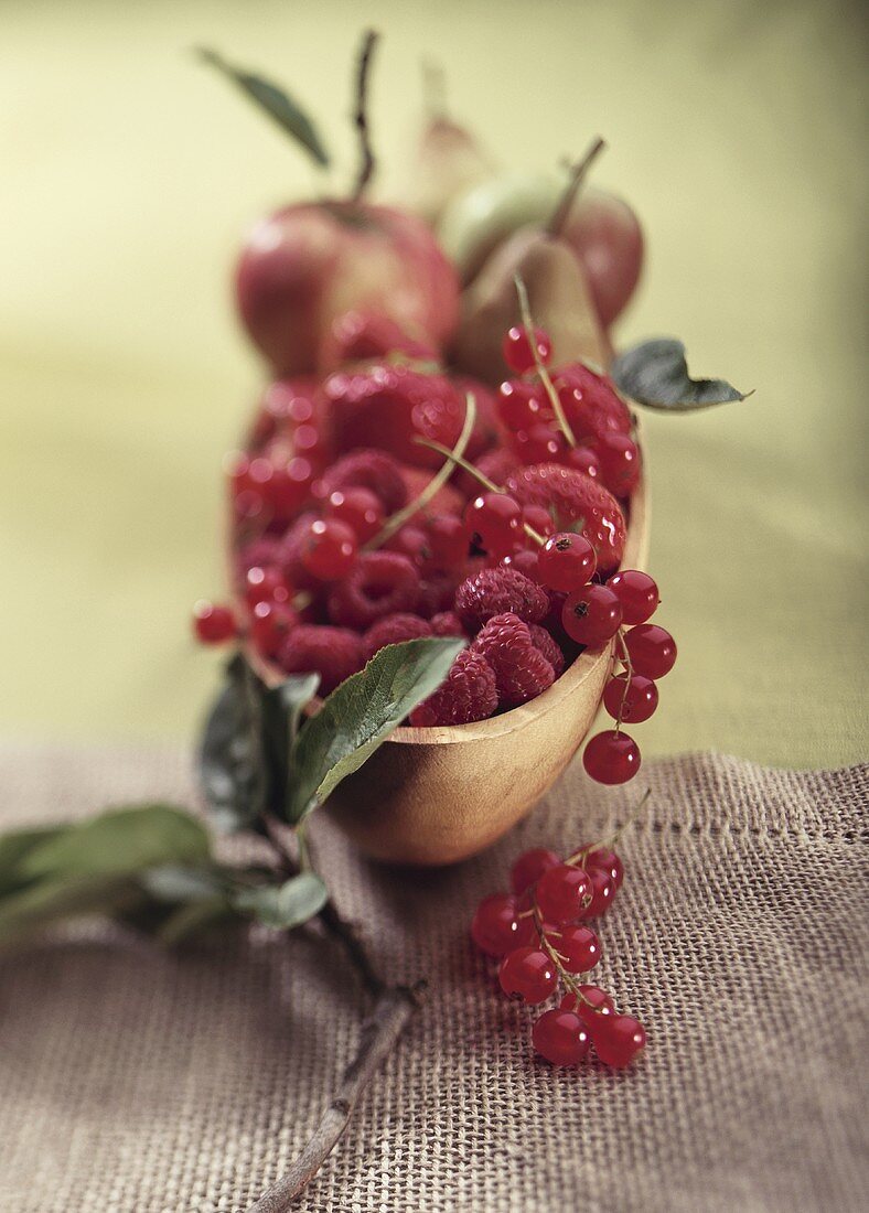 Red berries, apples and pears in a wooden bowl