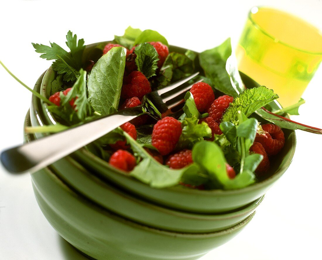 Herb salad with fresh raspberries in green bowl