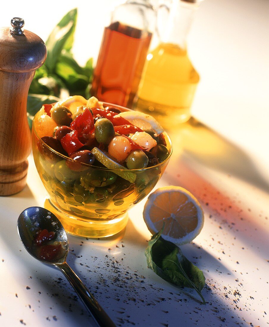 Bottled olives with lemons in glass bowl; vinegar; oil
