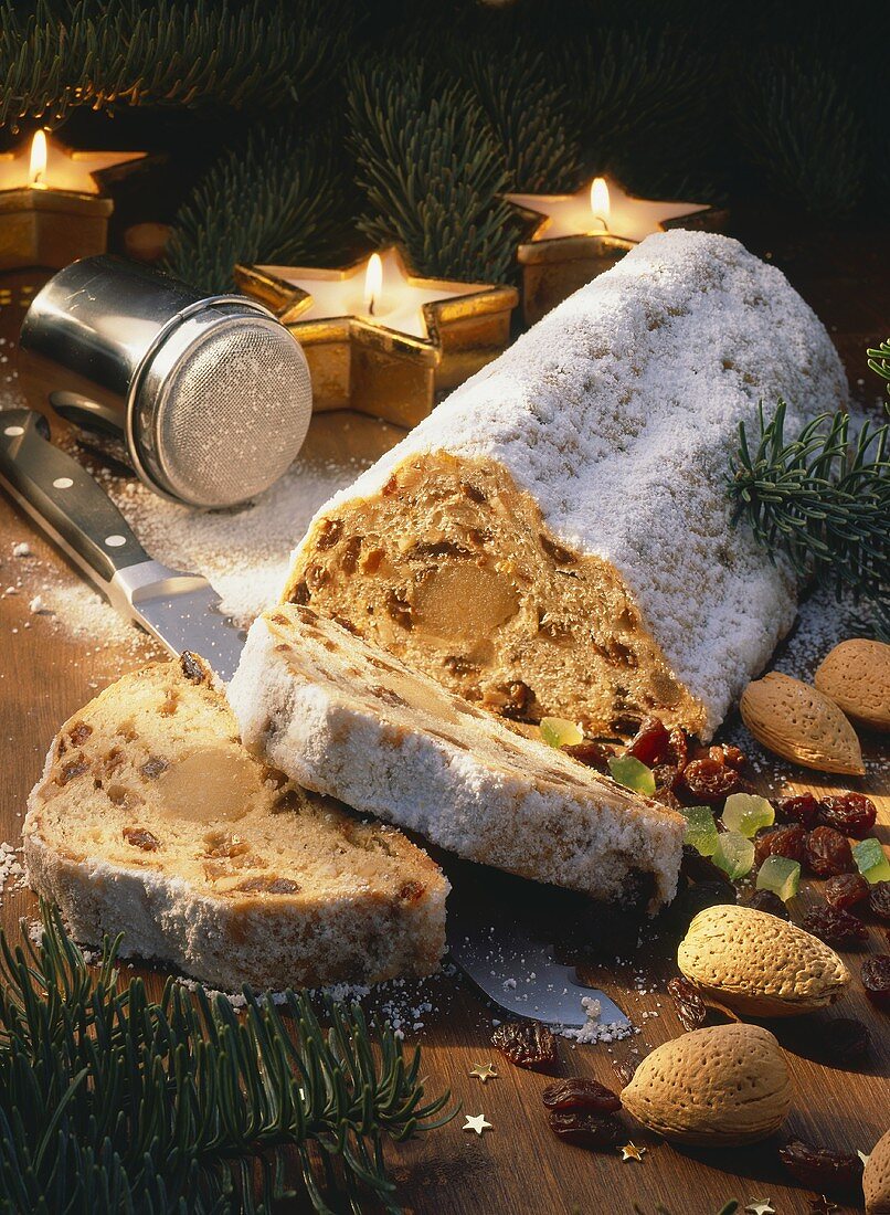 Weihnachtsstollen mit Zutaten, Kerzen und Tannenzweigen