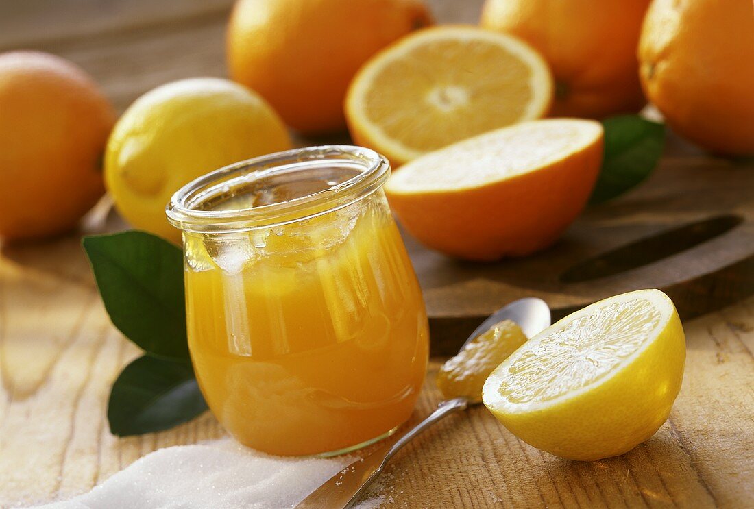 Orangengelee mit Zitronen im Glas; frische Zitrusfrüchte