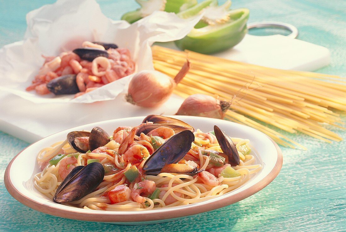 Spaghetti with seafood on plate in front of ingredients
