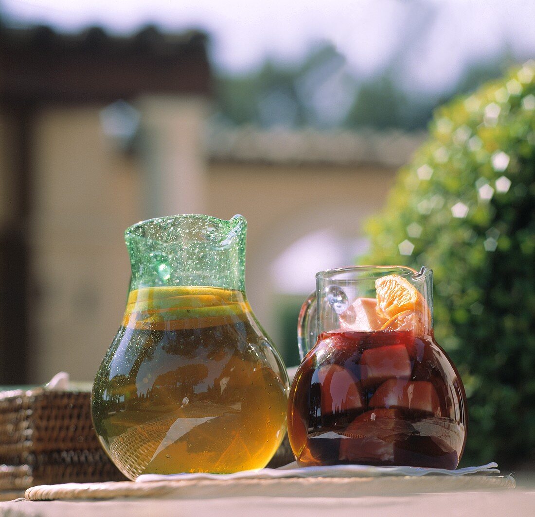 Sangria and iced tea in glass jugs on a stone wall