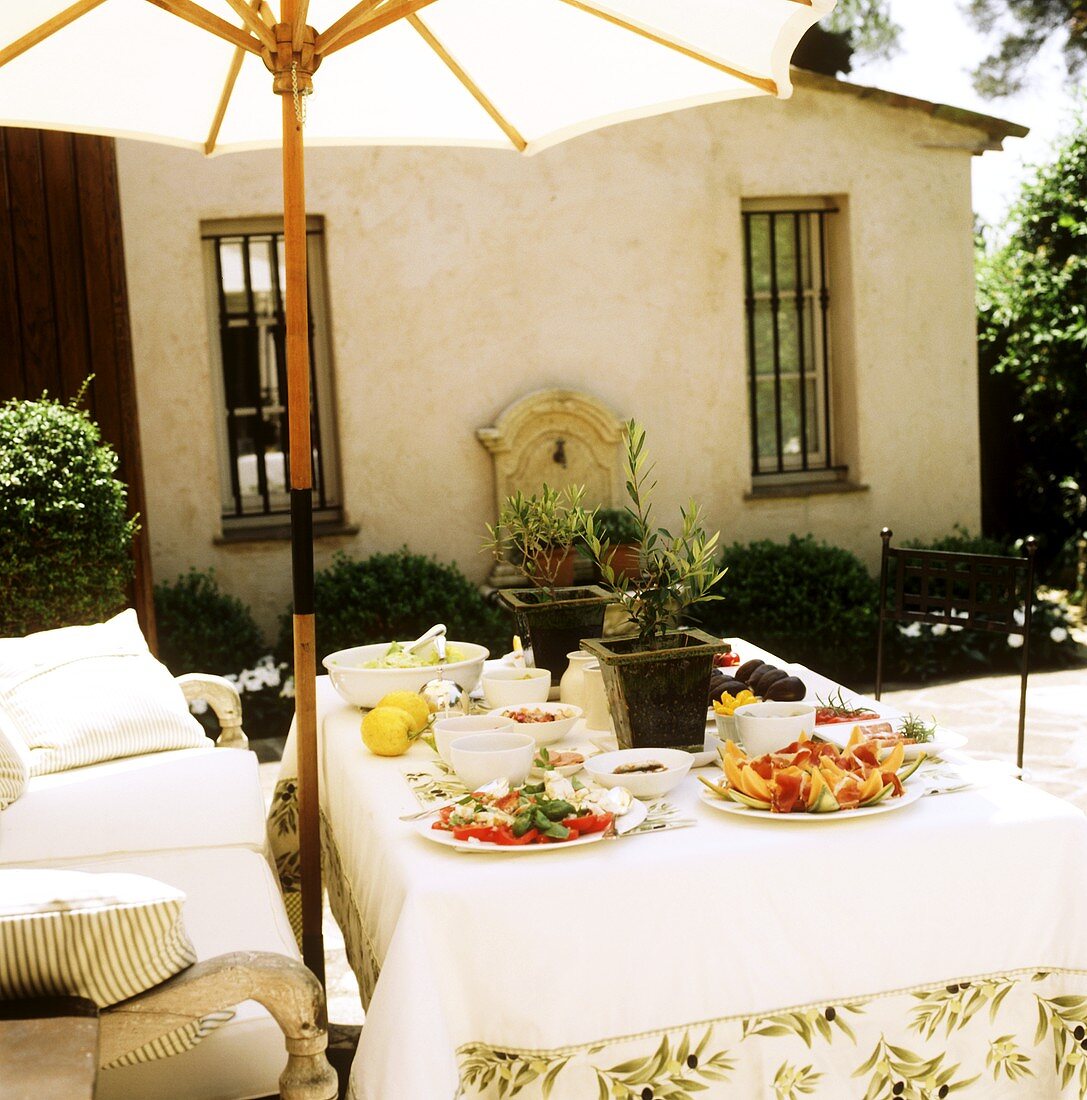 Italienisches Vorspeisenbuffet auf Tisch unter Sonnenschirm