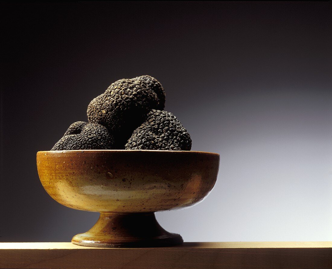 Black truffles in a brown ceramic bowl