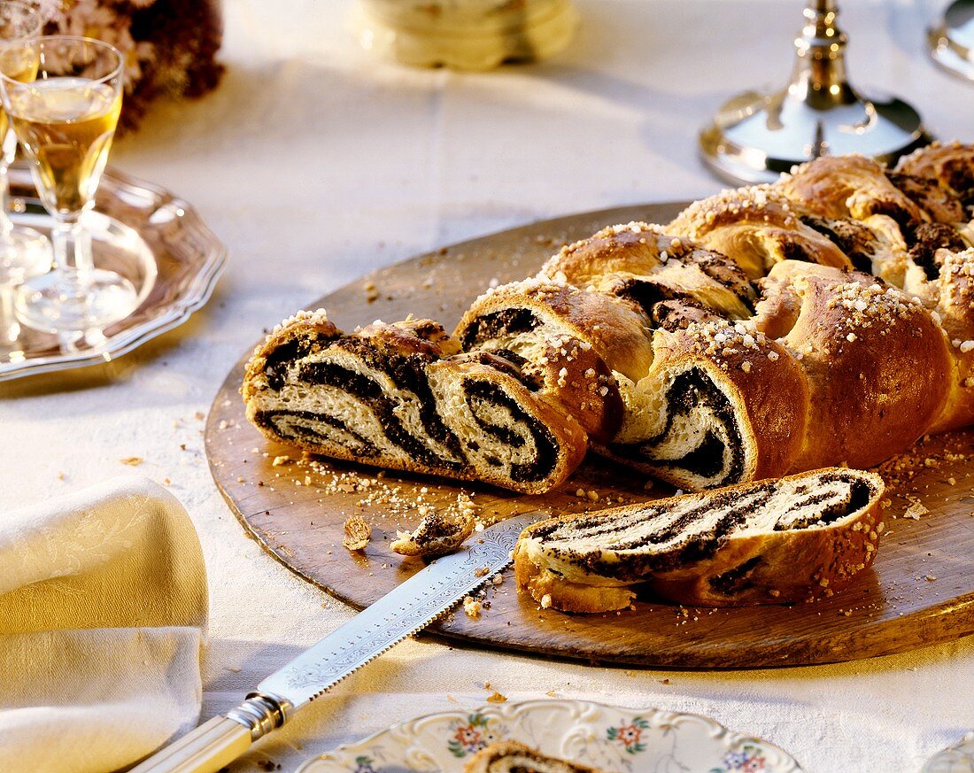 Yeast plait with poppy seeds and sugar on wooden plate