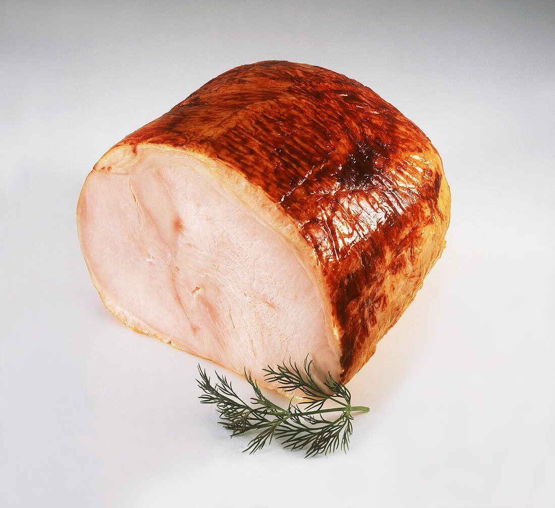 Ham on white background, garnished with dill