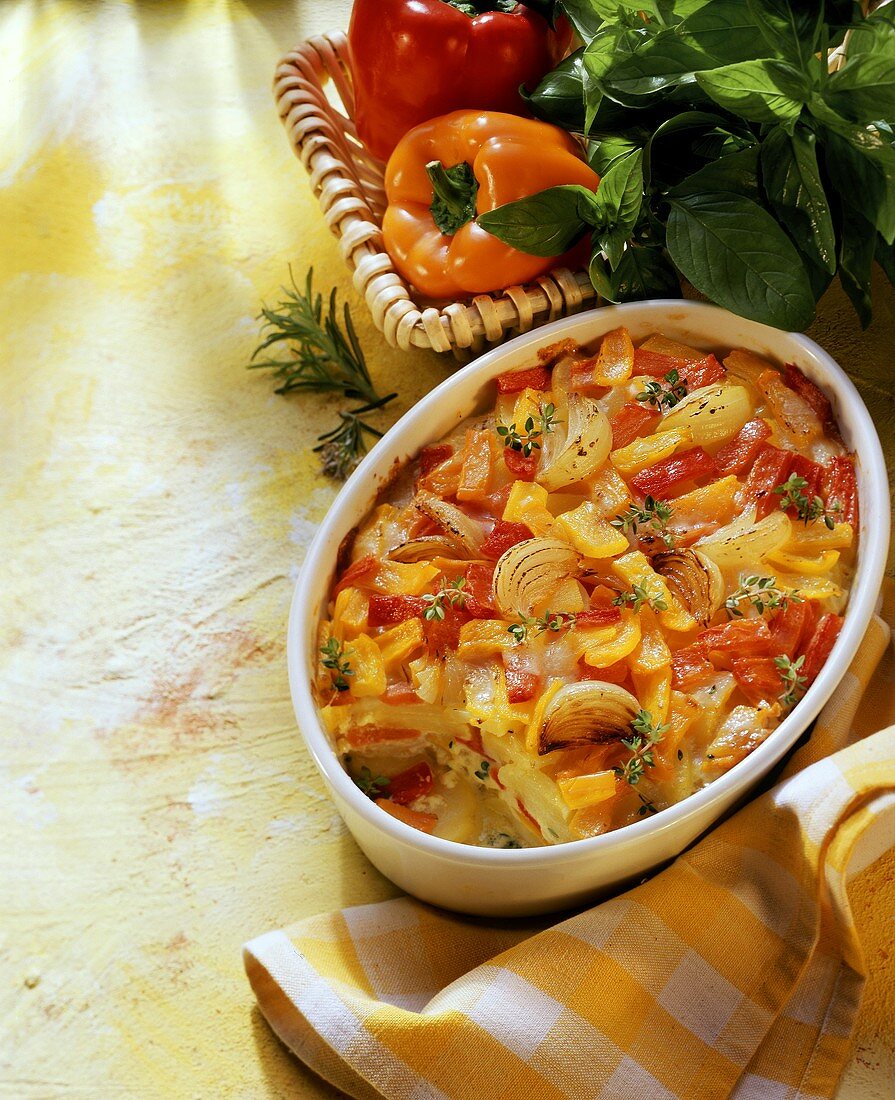 Ratatouille bake in white baking dish; peppers; herbs