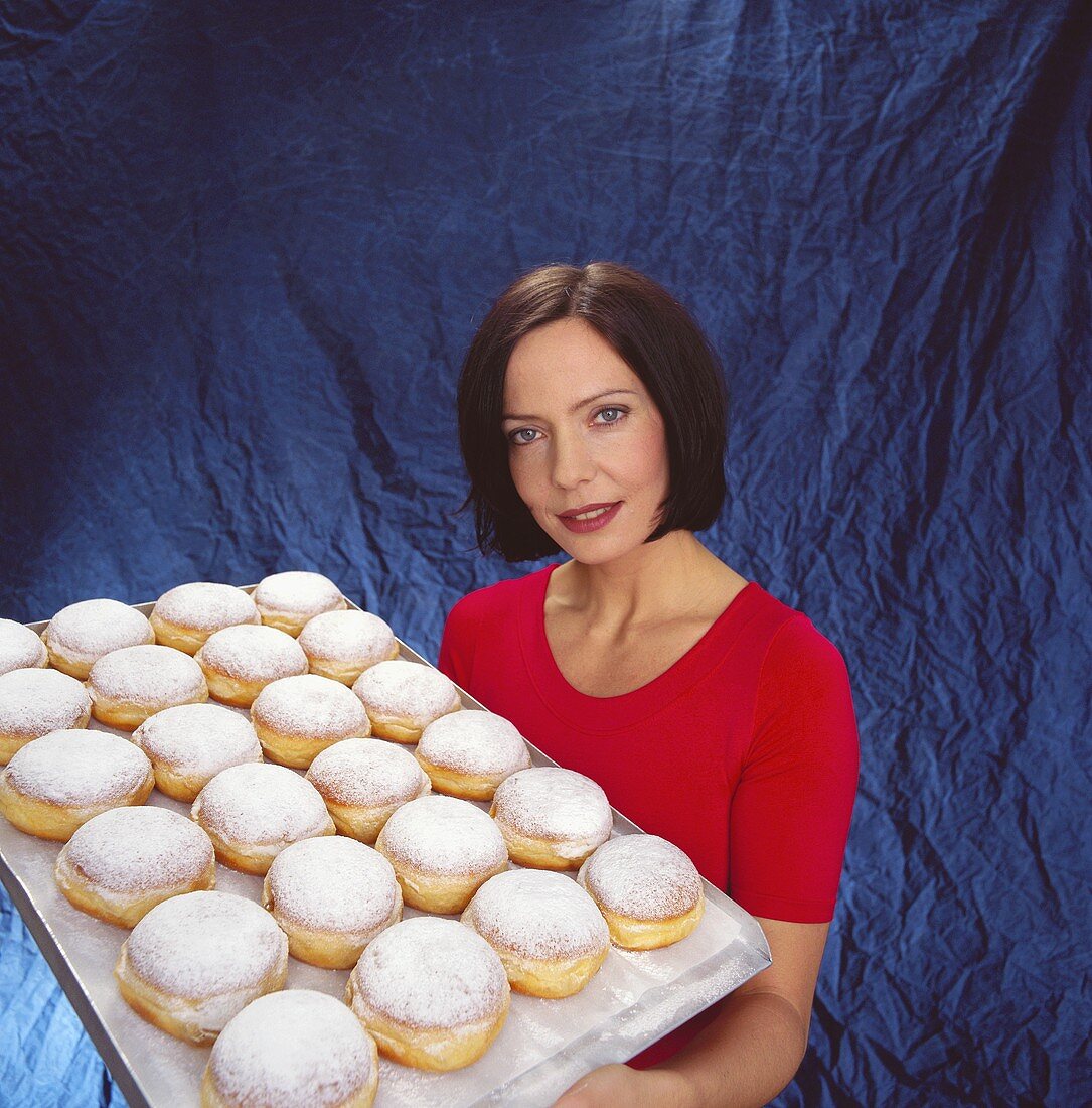 Frau hält Tablett mit frischen Krapfen