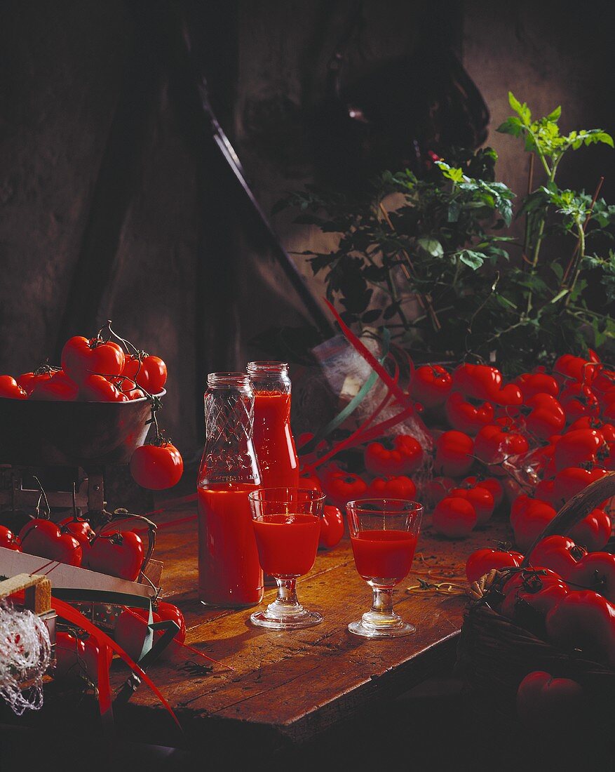 Tomatensaft in Flaschen und Gläsern, umgeben von Tomaten
