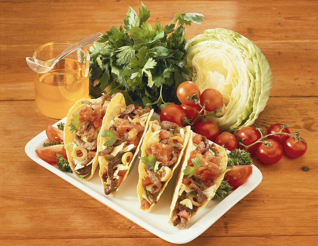 Tacos mit Fleisch, Tomaten und Oliven; Salat; Tomaten; Öl