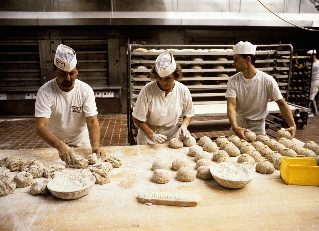 Baker forming loaves in a large bakery