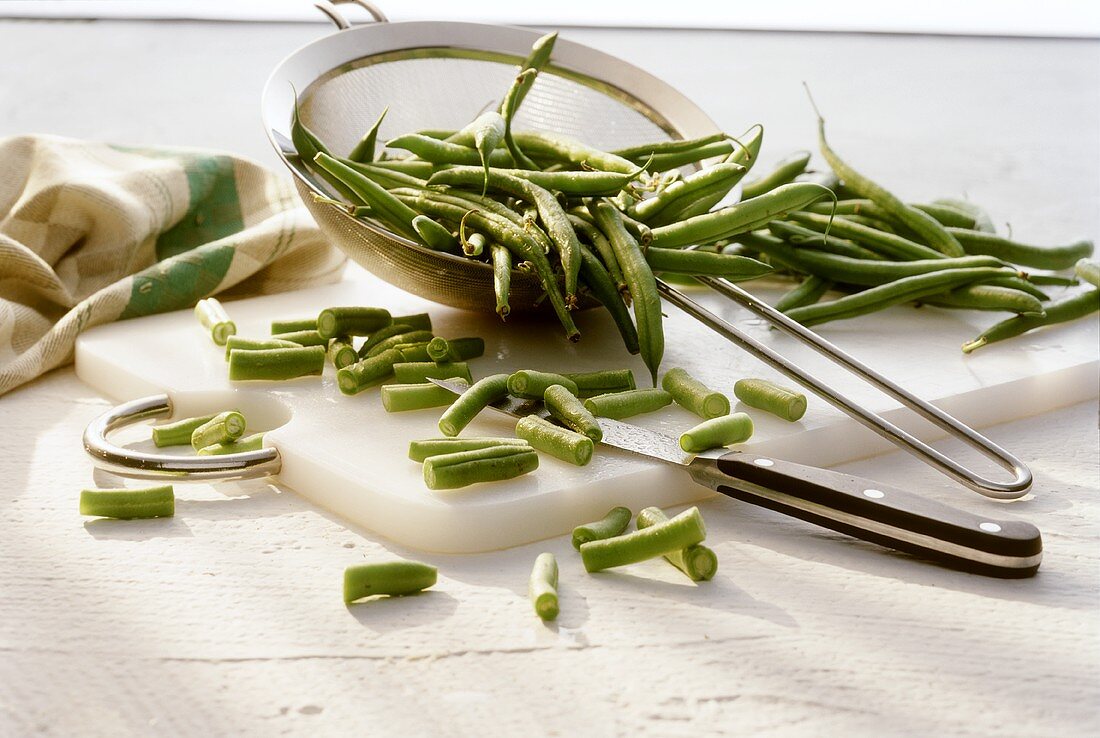 Green beans in sieve on chopping board