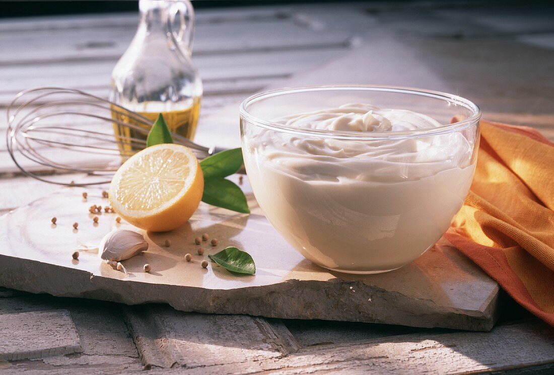 Mayonnaise in glass bowl, ingredients beside it