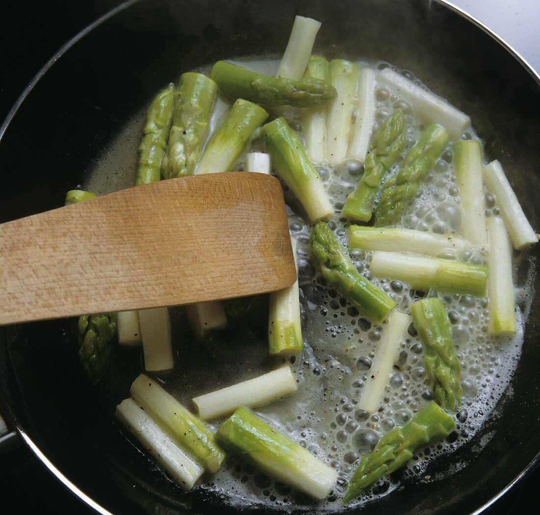 Tossing green asparagus in butter
