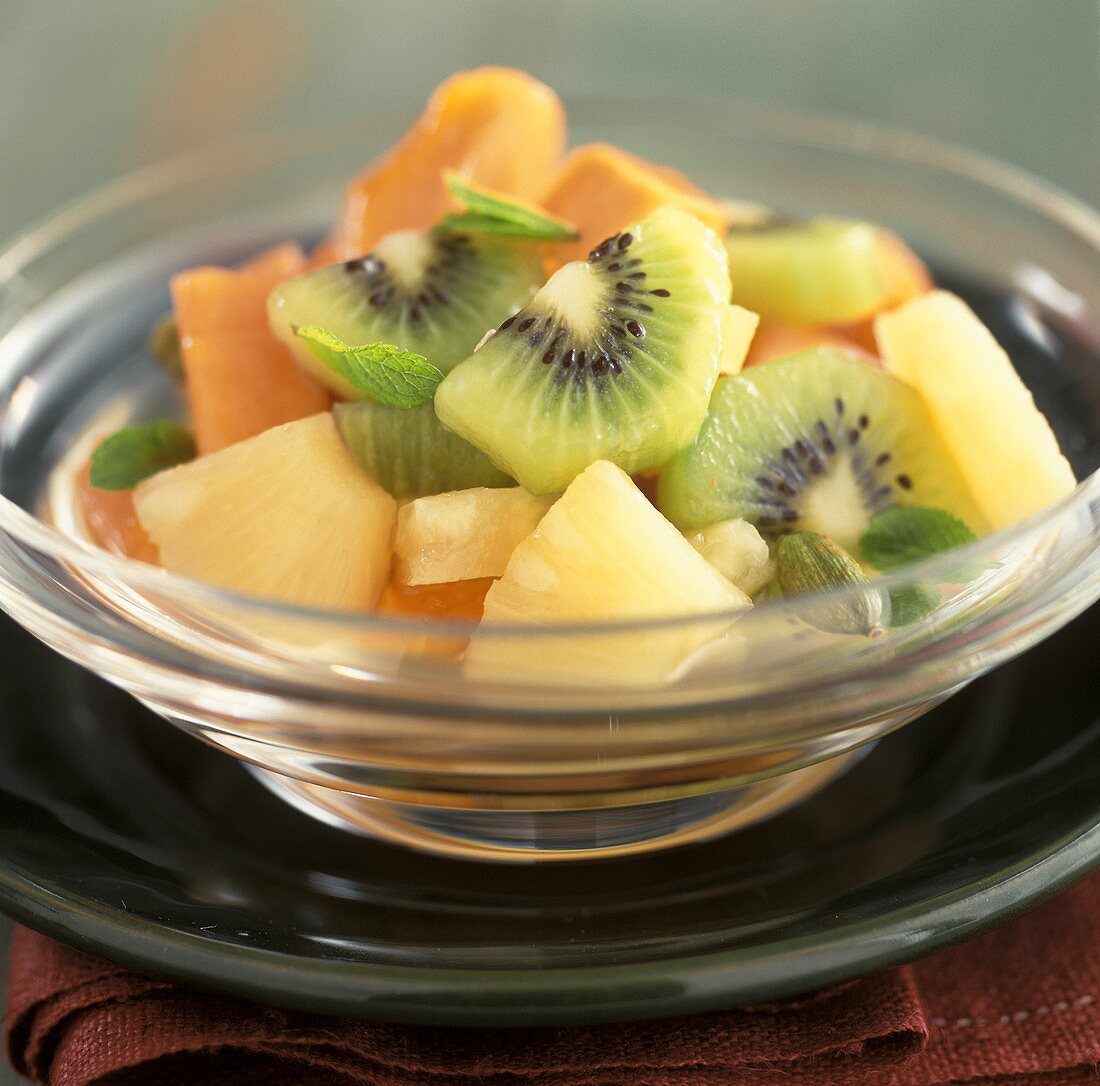 Fruit salad with kiwis and pineapple in a glass bowl