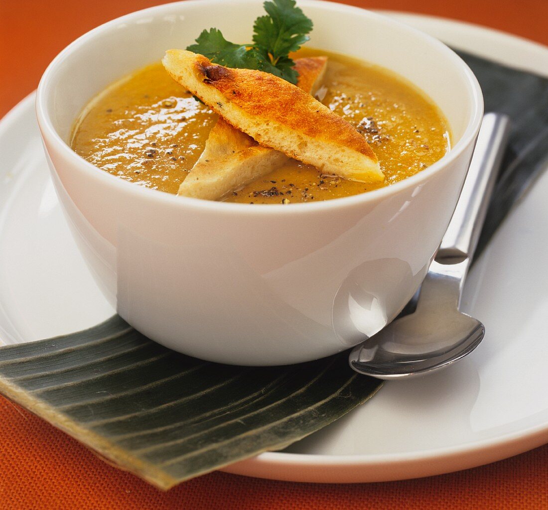Pumpkin soup with focaccia bread in a white bowl
