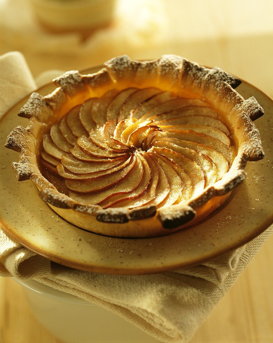 Apfel-Birnen-Tarte mit Puderzucker auf Teller