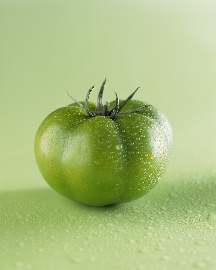 Eine grüne Tomate mit Wassertropfen