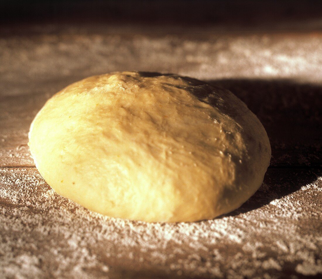 Bread dough with flour on a wooden table