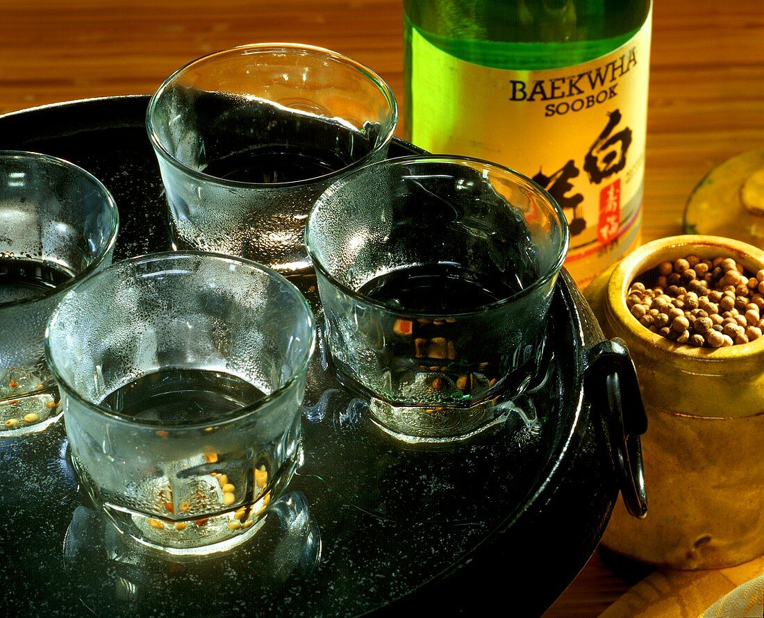 Reiswein in Gläsern auf Tablett, daneben Reisweinflasche