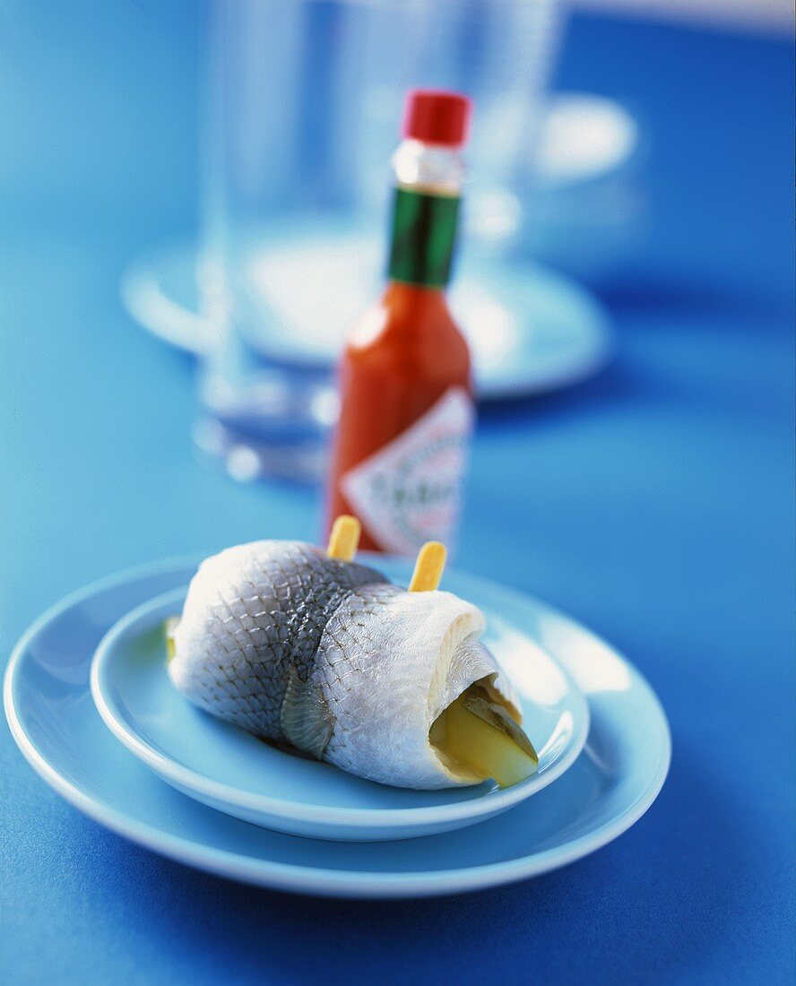 Rollmops auf Teller vor Tabascoflasche