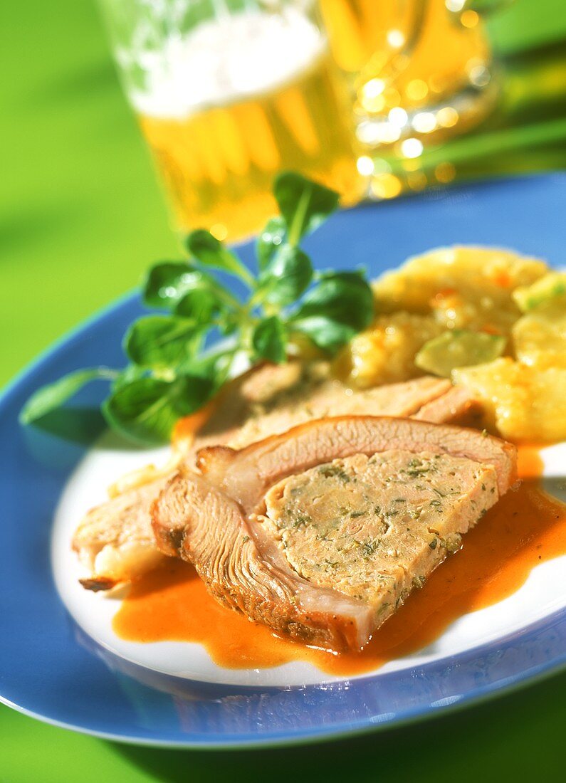 Stuffed veal breast with red wine sauce on plate; beer