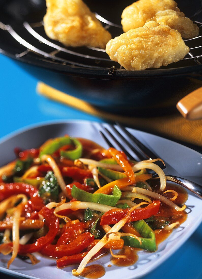 Crispy fish in wok and sweet & sour vegetables on plate