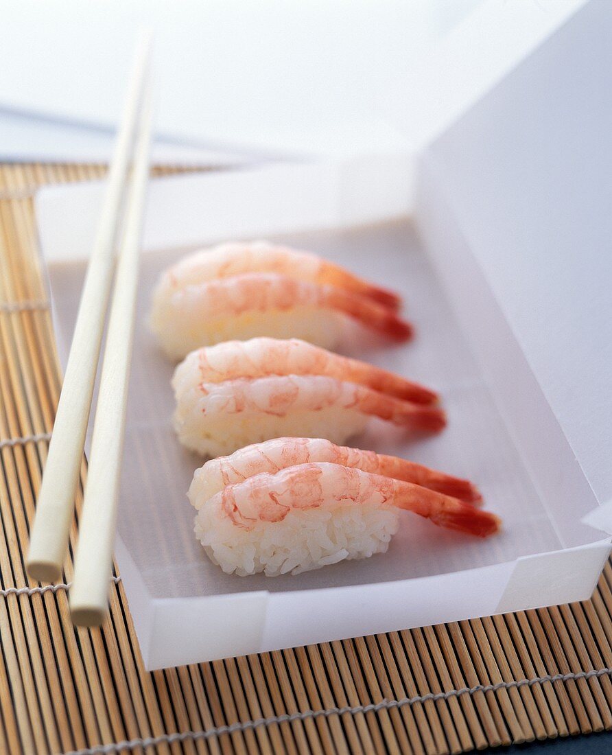 Nigiri sushi with shrimps in a white paper box