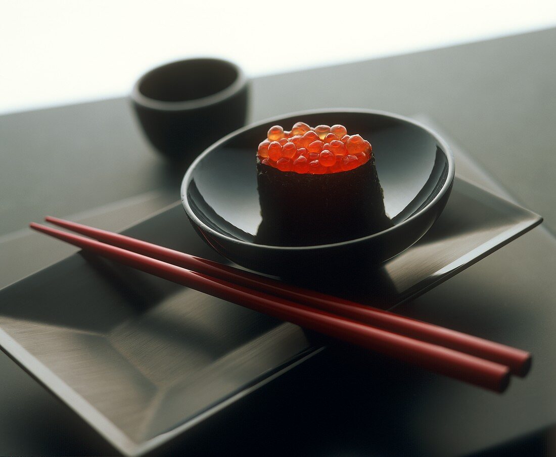 Ein Gunkan Maki mit Keta-Kaviar in schwarzem Schälchen