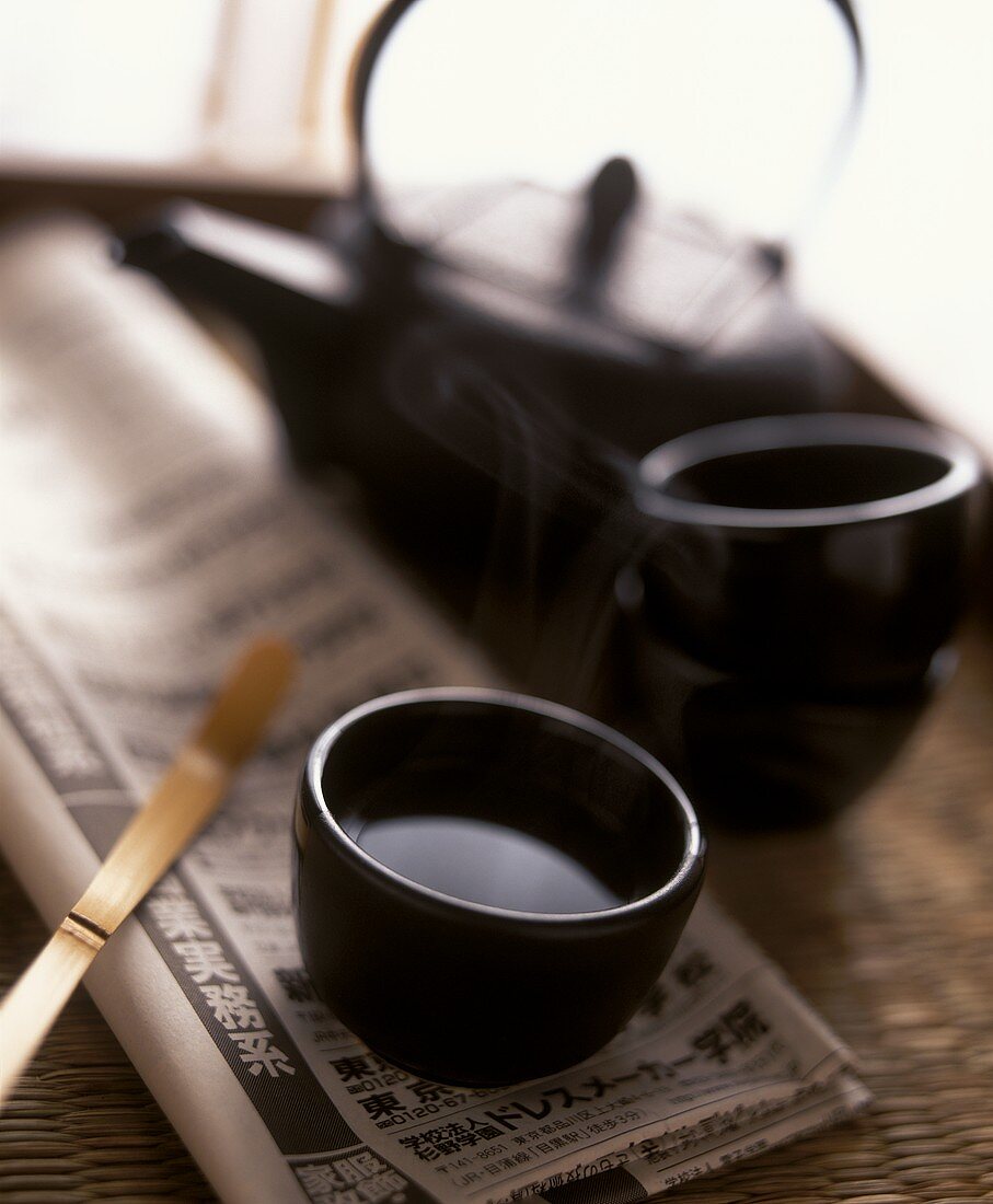 Grüner Tee in Schale auf japanischer Zeitung; Teekanne