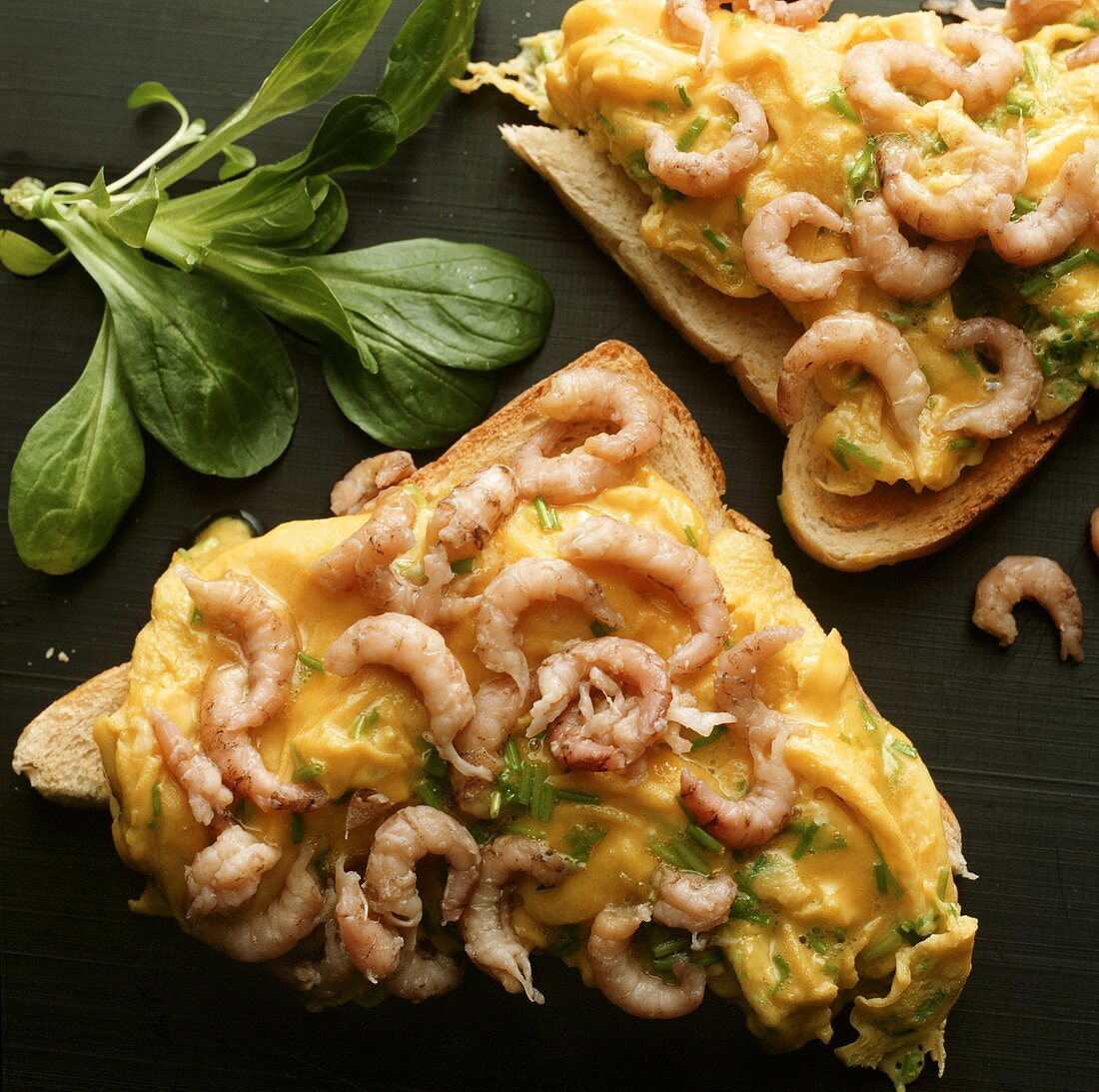 Two toasts with scrambled egg with shrimps; corn salad