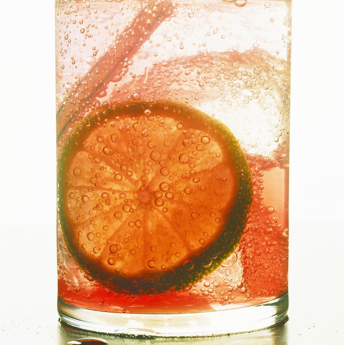 Fruit drink with slice of lime and ice cubes