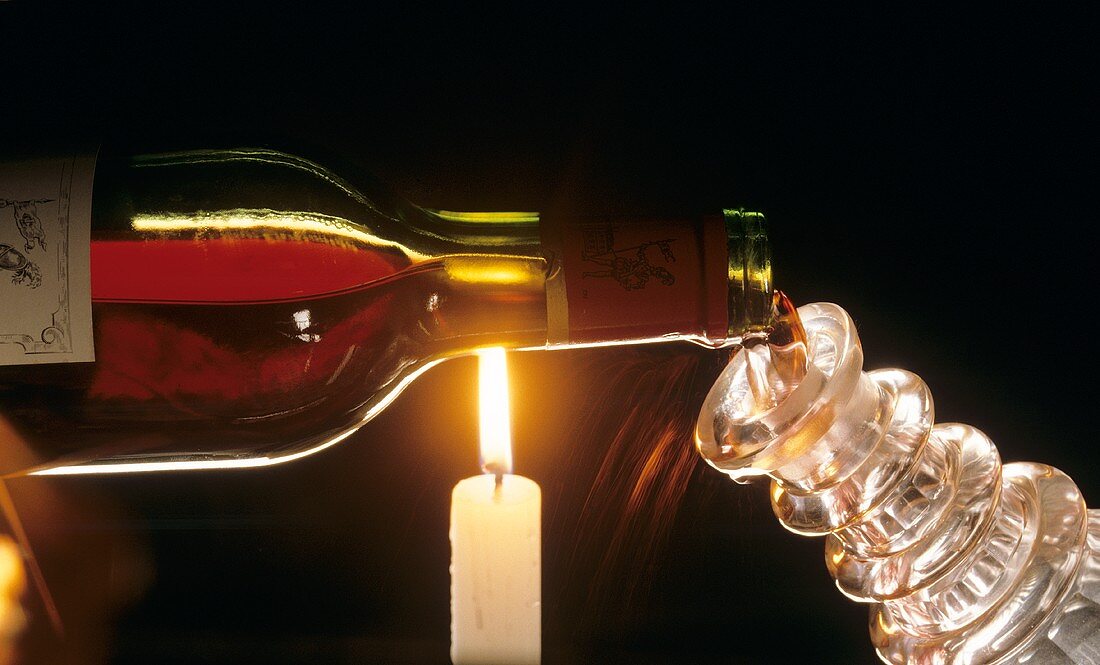 Rotwein über Kerzenflamme in Karaffe füllen