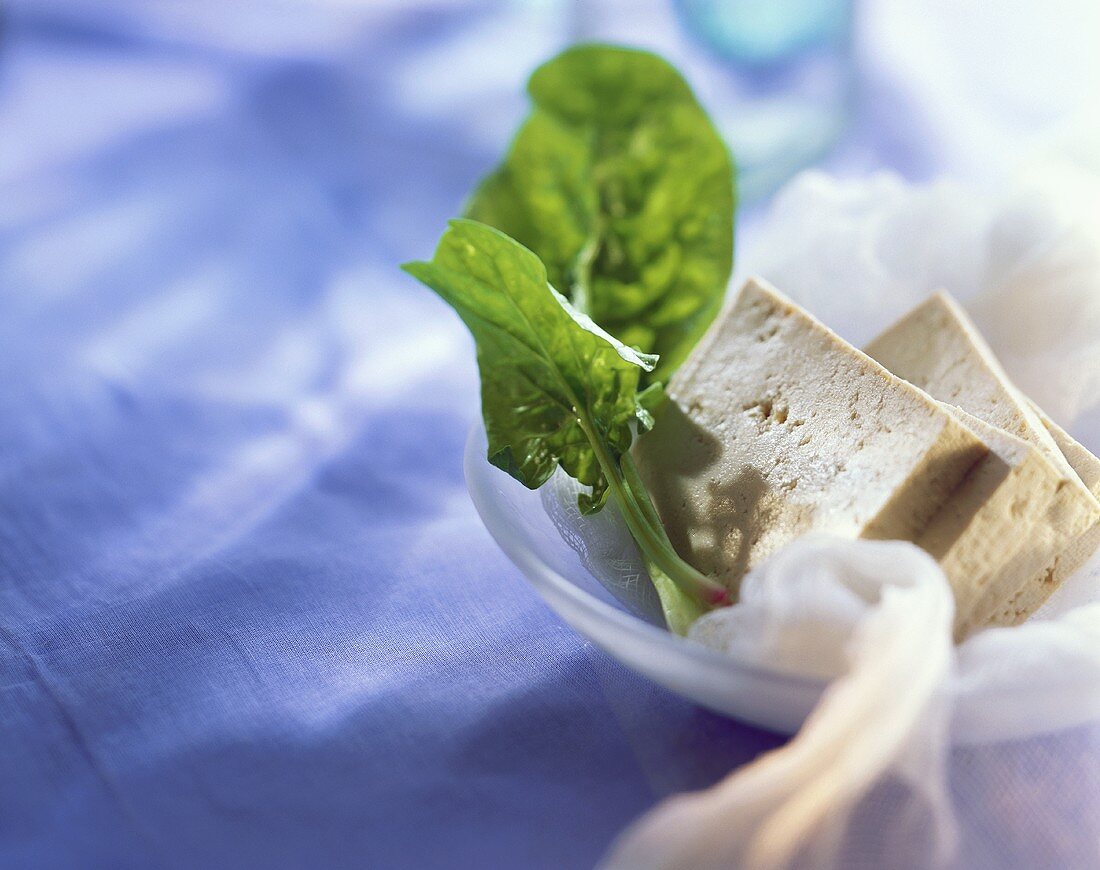 Tofu slices and fresh spinach in a bowl