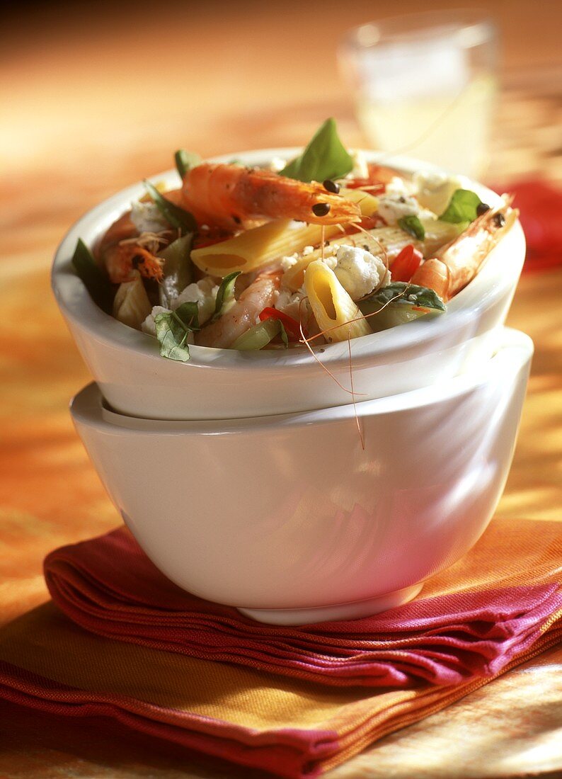 Pasta salad with sheep's cheese and shrimps in a white bowl