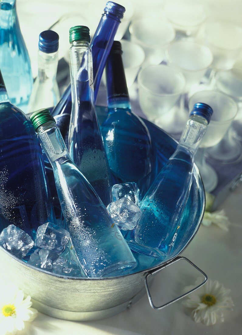 Mineralwasser- und Weinflaschen im Eiskübel, dahinter Gläser
