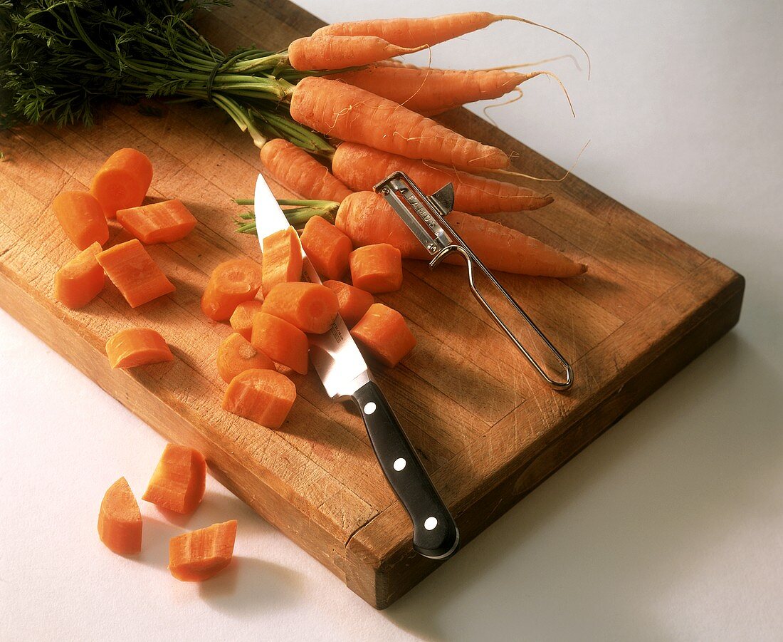 Carrots, partly sliced, with knife on chopping board