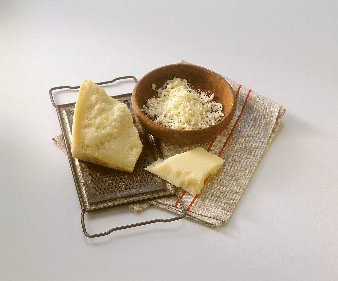 Pieces of Parmesan on grater and grated Parmesan in bowl