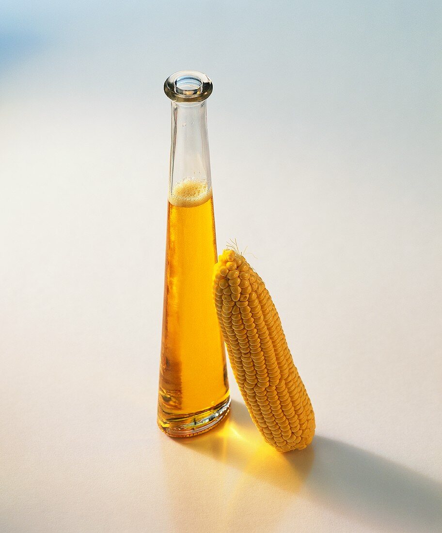 Corn oil in bottle beside corncob