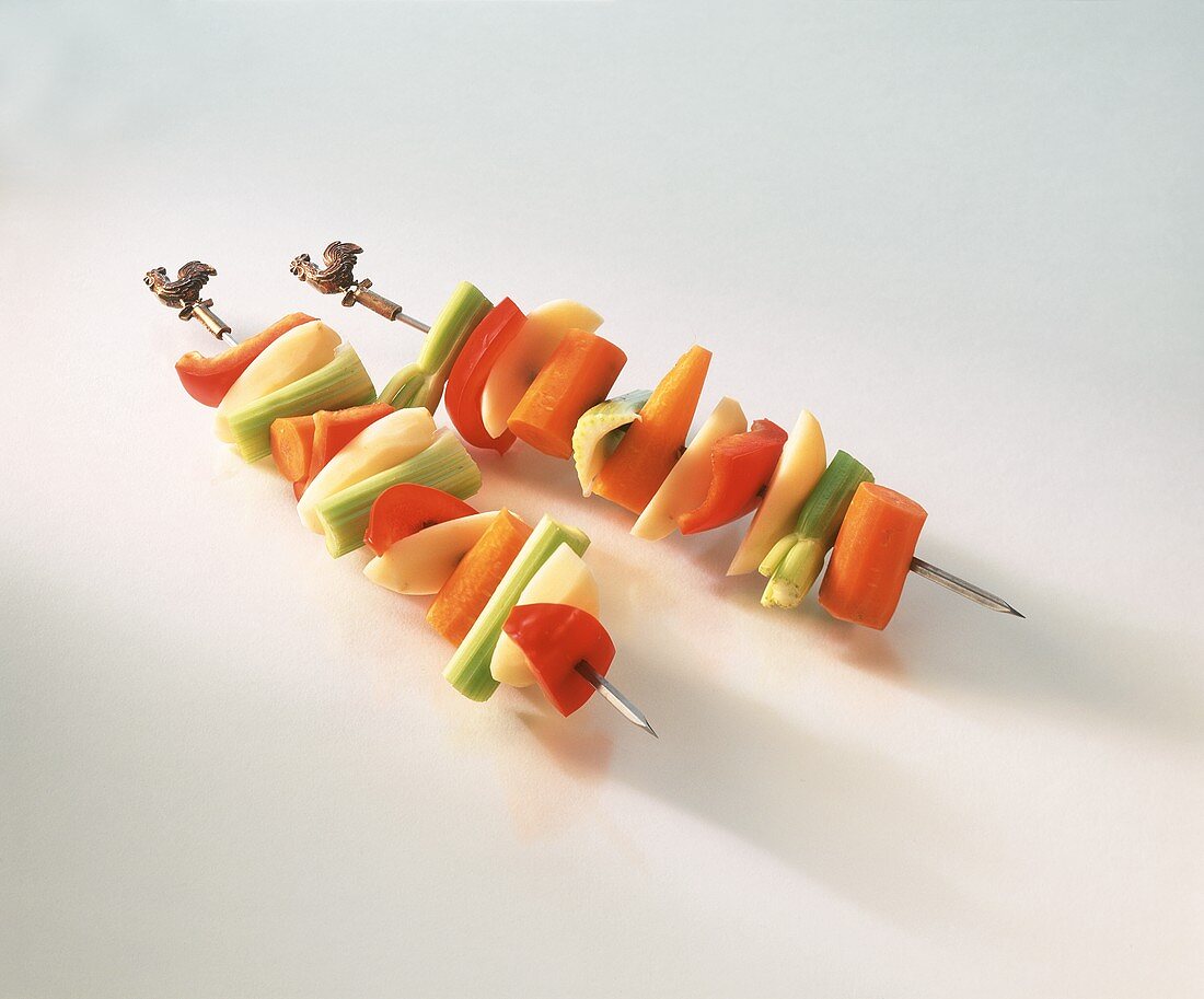 Raw vegetable kebabs on white background